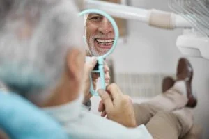 aged patient sitting dental chair while looking himself mirror